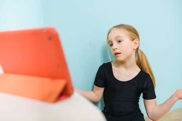 Little girl during video call, online class with tablet on desk looking at screen and communicate at social distancing, self-isolation time