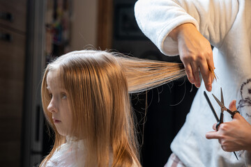 hair cutting at home, mom cuts daughter's hair in the kitchen