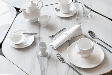 Fototapeta na wymiar White table setting. Elegant empty plate, cutlery, napkin and cup, for breakfast. Selective Focus