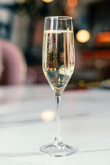 A glass of champagne on a white table in a cafe. Selective Focus