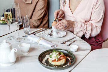 Obraz na płótnie Canvas A woman peels an egg for breakfast in a restaurant. Selective Focus