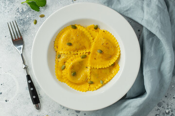 Homemade Pumpkin Ravioli with butter on a light concrete background. Top view