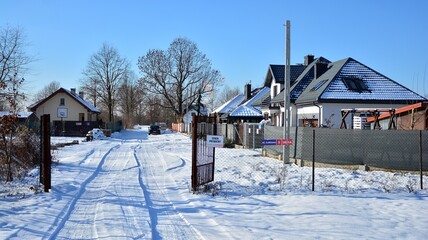 Residential neighborhood in the suburbs during a white snow storm and roads covered in snow. 