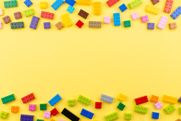 Colored toy bricks with with space for text. Toy yellow background.