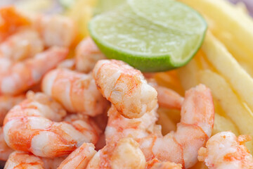 Shrimp snack accompanied by potato. Traditional taste of beaches in northeastern Brazil. Juicy shrimp served with fries and green lemon on the beach. 