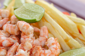 Shrimp snack accompanied by potato. Traditional taste of beaches in northeastern Brazil. Juicy shrimp served with fries and green lemon on the beach. 