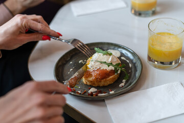 Woman hands holding fork and knife and having breakfast. Smoked salmon sandwich with cream cheese on plate close-up, glass of orange juice, napkin. Selective Focus