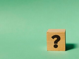 Question mark concept.Wooden cube with question mark symbol isolated on bluish background.