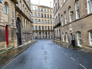 Fototapeta premium Looking along, Vicar Lane, with Victorian stone built mills, on a wet day in, Little Germany, Bradford, UK