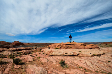 Man standing on rock in Arizona Desert landscape, looking out.