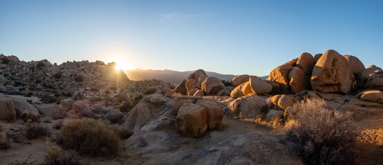 Last light of sunset behind rocks and boulders in panoramic view of desert landscape on a sunny...
