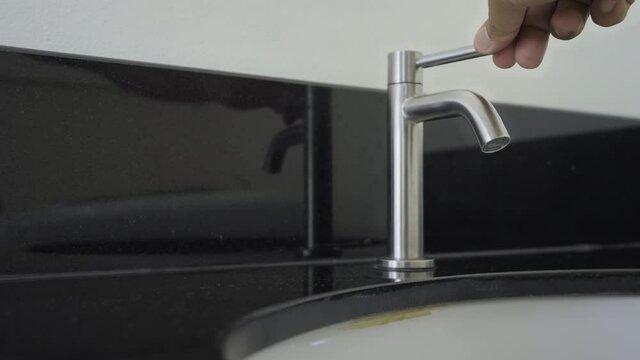 Water flowing in wash basin, Slow motion man hand turn on water vale,Close up man keeps open water tap, Turning on chrome faucet in the bathroom, Concept water is energy and protect the environment.