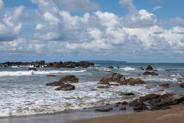 Fototapeta na wymiar Rocky beach with blue water and blue sky and rocks at Corcovado National Park, Costa Rica.