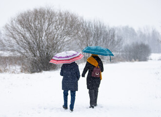 

two women walking in winter with umbrellas, Poland