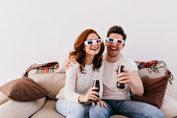 Funny young people watching movie in 3d glasses. Couple spending valentine's day at home.