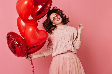 Stunning girl having fun in valentine's day. Studio photo of carefree lady isolated on pink with red balloons.