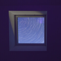 looking into night sky outside through window with star trails circular from polaris above