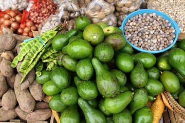 Avocados, bitter bean, sweet potato, potato and onion at a traditional shop. Focus selection in avocado