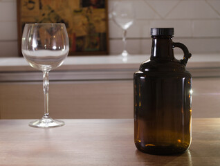 Growler bottle for craft beer and empty glass on a counter.
