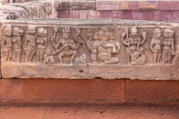 Aihole, Karnataka, India - November 7, 2013: Huchchimalli Gudi or Temple. Closeup of small brown stone fresco featuring Ganesha at center on red stone wall of tank.