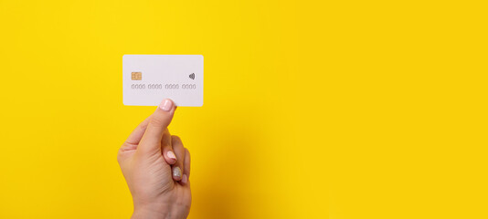credit card in hand over yellow background, panoramic image
