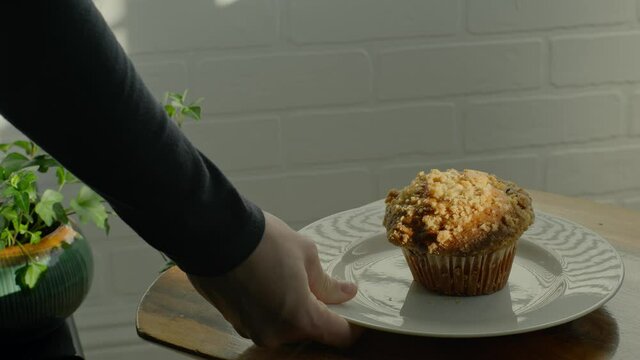 Blueberry muffin breakfast being placed on table in morning sunlight 