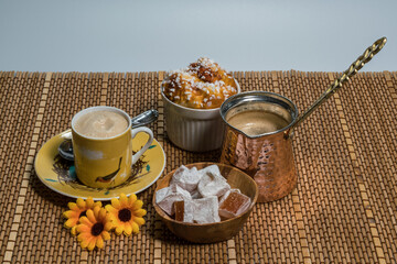 Turkish coffee in a copper pot and a coffee cup with turkish delight and pastry