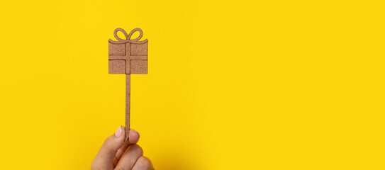 wooden gift in hand over yellow background