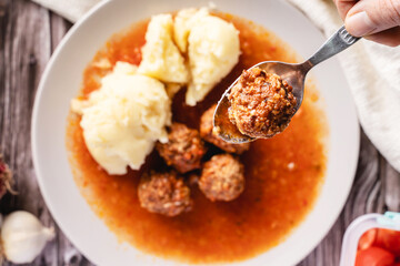 Top view on meat balls in a plate with tomato sauce and mashed potatoes on wooden rustic table - homemade food healthy eating traditional meal copy space