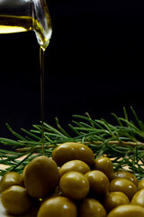 Glass bottle with virgin olive oil on a table with olives. Selective focus