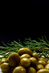 Glass bottle with virgin olive oil on a table with olives. Selective focus