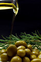 Glass bottle with virgin olive oil on a table with olives. Selective focus