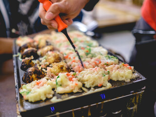 Cooking takoyakis at restaurant in Shinsekai district, Osaka, Japan