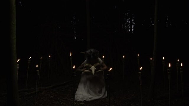 Woman Lifting Goat'S Skull In Dark Candlelit Forest