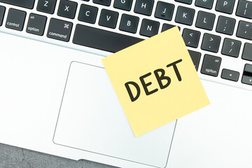 Debt-text on yellow sticky notes located on the laptop.