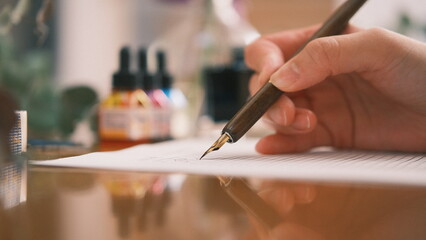 person writing on a paper with a calligraphy pen