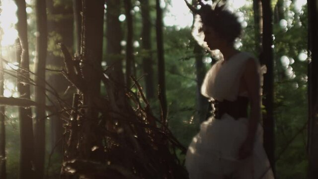 Woman In Headdress Walking Through Sunlit Forest