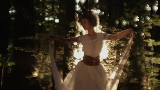 Woman Dressed In Horned Headdress Dancing In Sunlit Forest