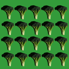 Broccoli pattern on a solid green background. Healthy diet. Colorful and fresh food. Broccoli cabbage. Photographed in harsh light so it has heavy, dark and sharp shadows. Top view. Flat lay.
