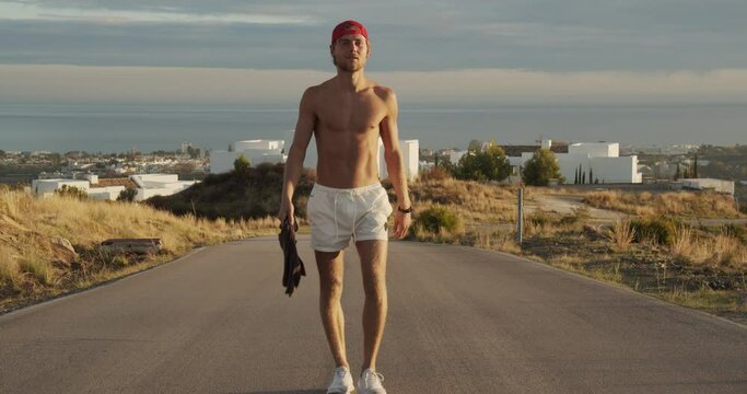 Man Walking Along Empty Road In Shorts
