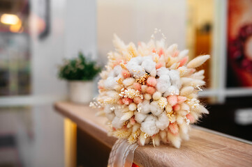 stylish dried flower pastel colors bouquet from cereal ears cotton and craspedia on counter of flower shop. reasonable consumption of natural materials, picking bouquets hobby