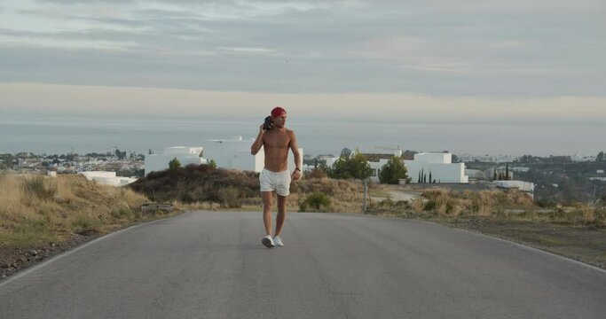 Shirtless Man In Shorts Walking Empty Road