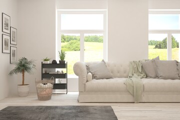 Fototapeta premium White living room with sofa and summer landscape in window. Scandinavian interior design. 3D illustration