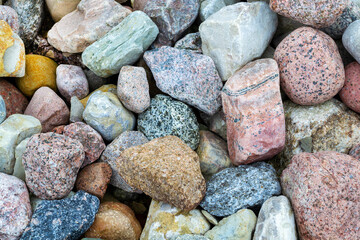 Close-up of multicolored colorful pebbles on a beach. Abstract nature background, texture. Beautiful small sea stones. Blue, pink, brown, orange, grey color.