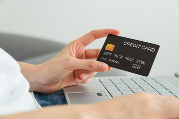 Hands holding credit card and using laptop with paying for shopping online.