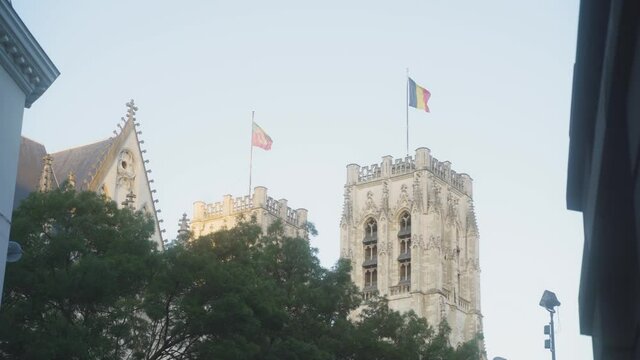 Belgian flag waving on top of the gothic Cathedral of St. Michael and St. Gudula in the city centre of Brussels, Belgium, on a warm sunny day with clear blue skies.