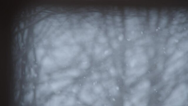 Snowflakes falling in SLOW MOTION. Focused on inside of windowpane.
