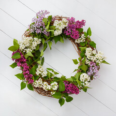 Wreath from white and purple lilac flowers on white wooden background. Midsummer bouquet from lilac for celebrate Juhannus day. Spring wreath. Easter holiday decoration. 