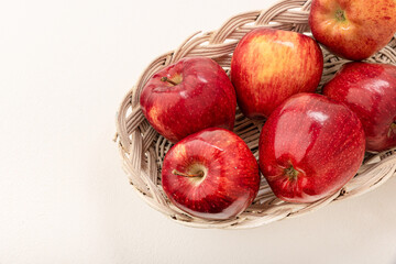 Apples red-yellow, juicy in a wicker basket on a light background