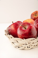 Apples red-yellow, juicy in a wicker basket on a light background